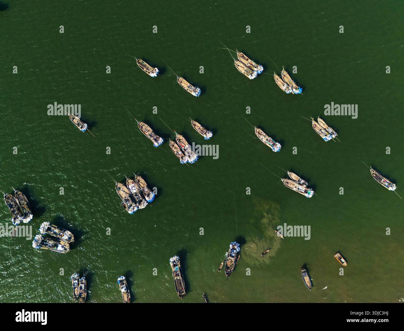 Cox's Bazar, Bangladesh - 8 febbraio 2025: Vista aerea delle barche da pesca sparse come foglie cadute sulle scintillanti acque verdi della baia Foto Stock