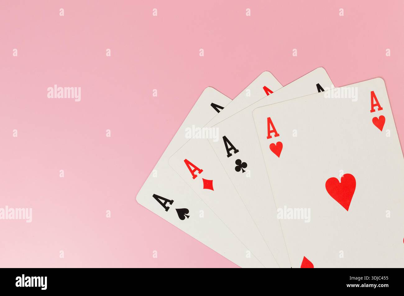 Vista dall'alto delle carte da gioco su sfondo rosa. Quattro carte assi, gioco da tavolo, poker. Copia spazio, disposizione piatta. Foto Stock