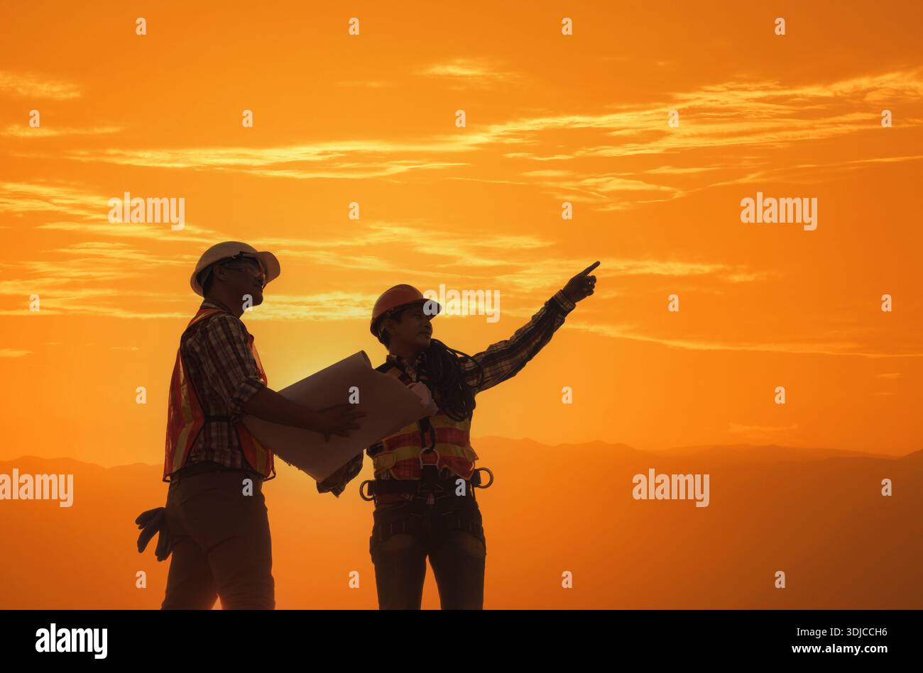 Sagoma di due operai edili che guardano i progetti di un cantiere al tramonto, in Thailandia Foto Stock