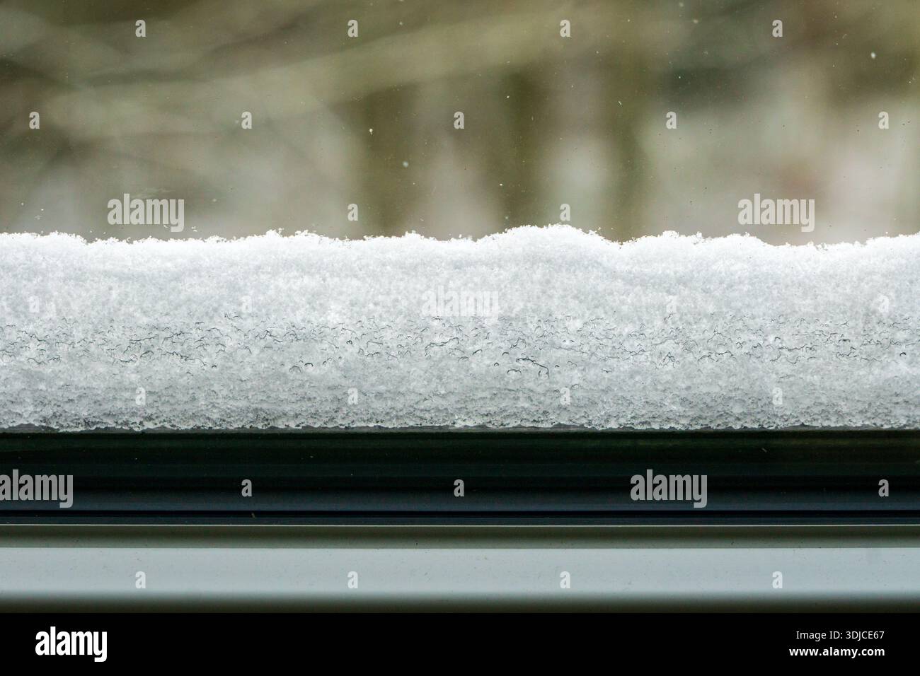 Vista ravvicinata di uno strato di neve fresco che poggia su un davanzale durante l'inverno. Foto Stock