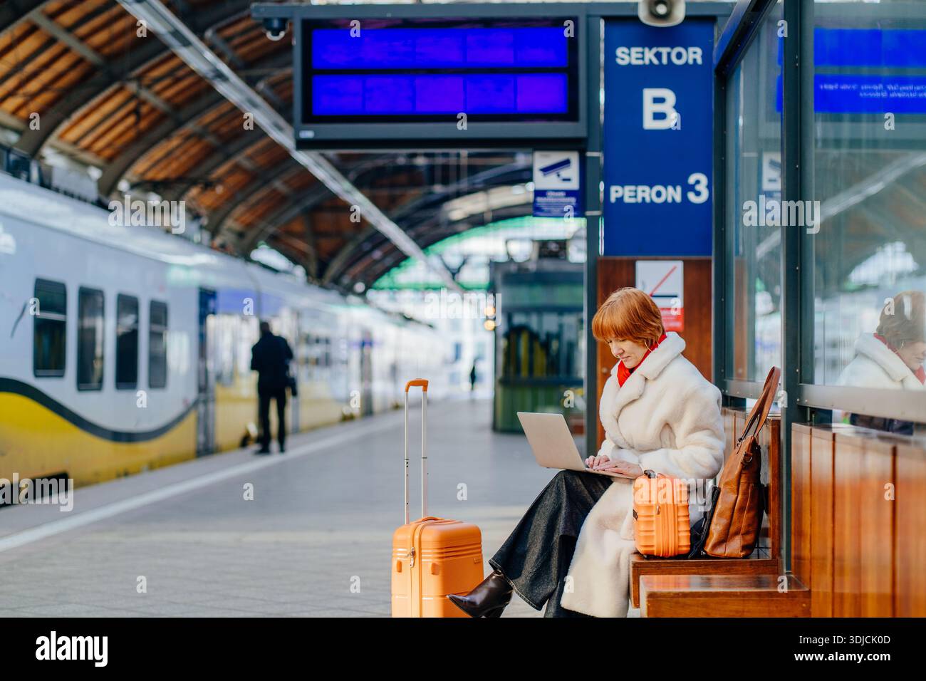 Donna rossa caucasica di mezza età sicura che sta pianificando un lavoro con un laptop durante la fermata del treno Foto Stock
