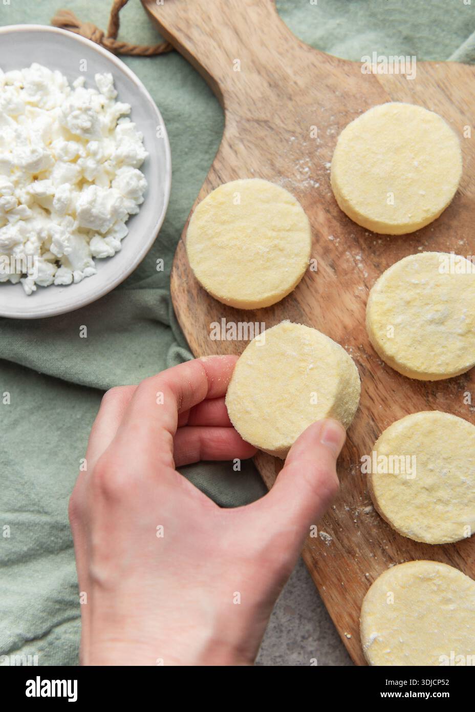Mettere a mano i pancake di sciroppo crudi fatti di quark su un asse di legno per la cottura Foto Stock