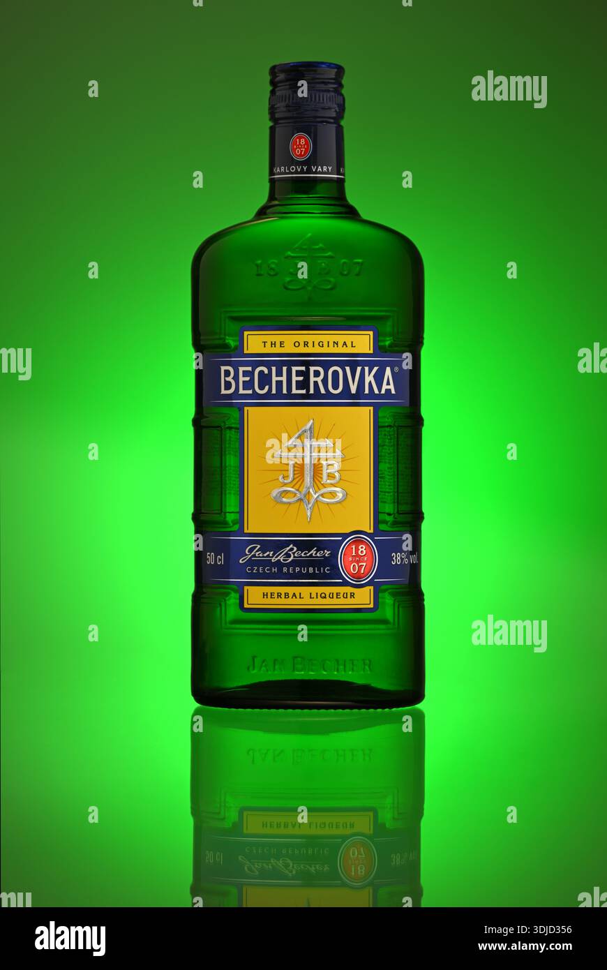 Una bottiglia di Becherovka si trova su uno sfondo verde. Il flacone è verde e ha un'etichetta gialla Foto Stock