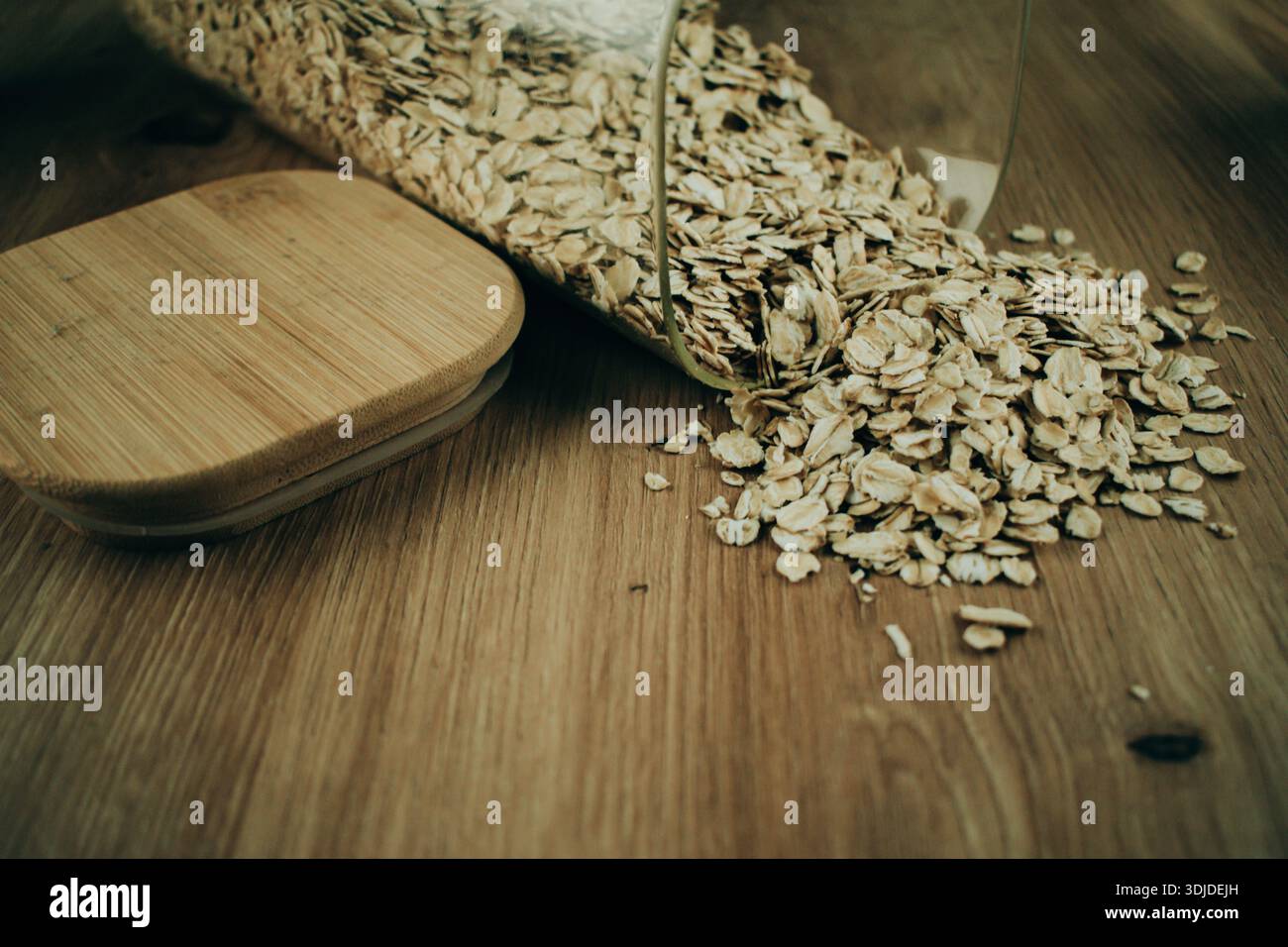 Avena versata su un tavolo di legno, che mostra la consistenza della grana e una semplice scena alimentare con materiali naturali. Foto Stock