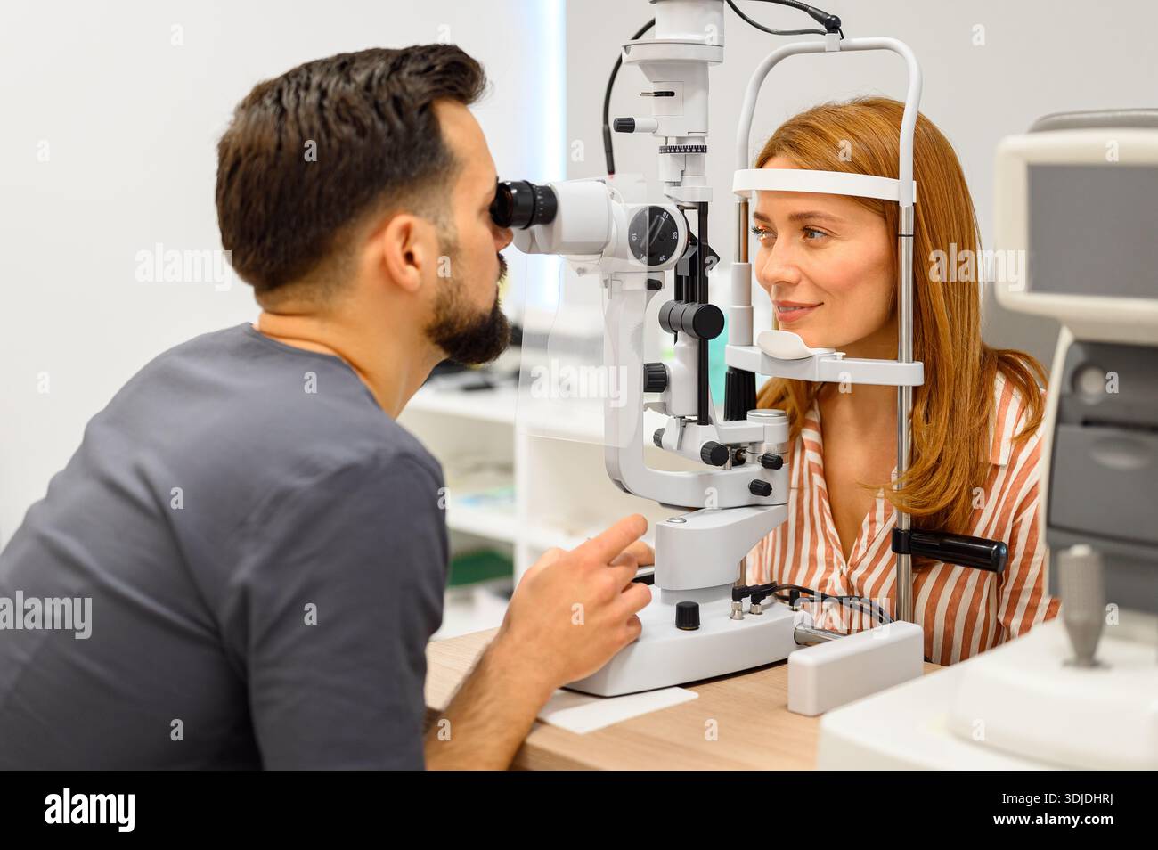 Oftalmologo maschile che esegue un esame oculare con lampada a fessura su paziente durante il check-up presso la moderna clinica di cura della vista Foto Stock