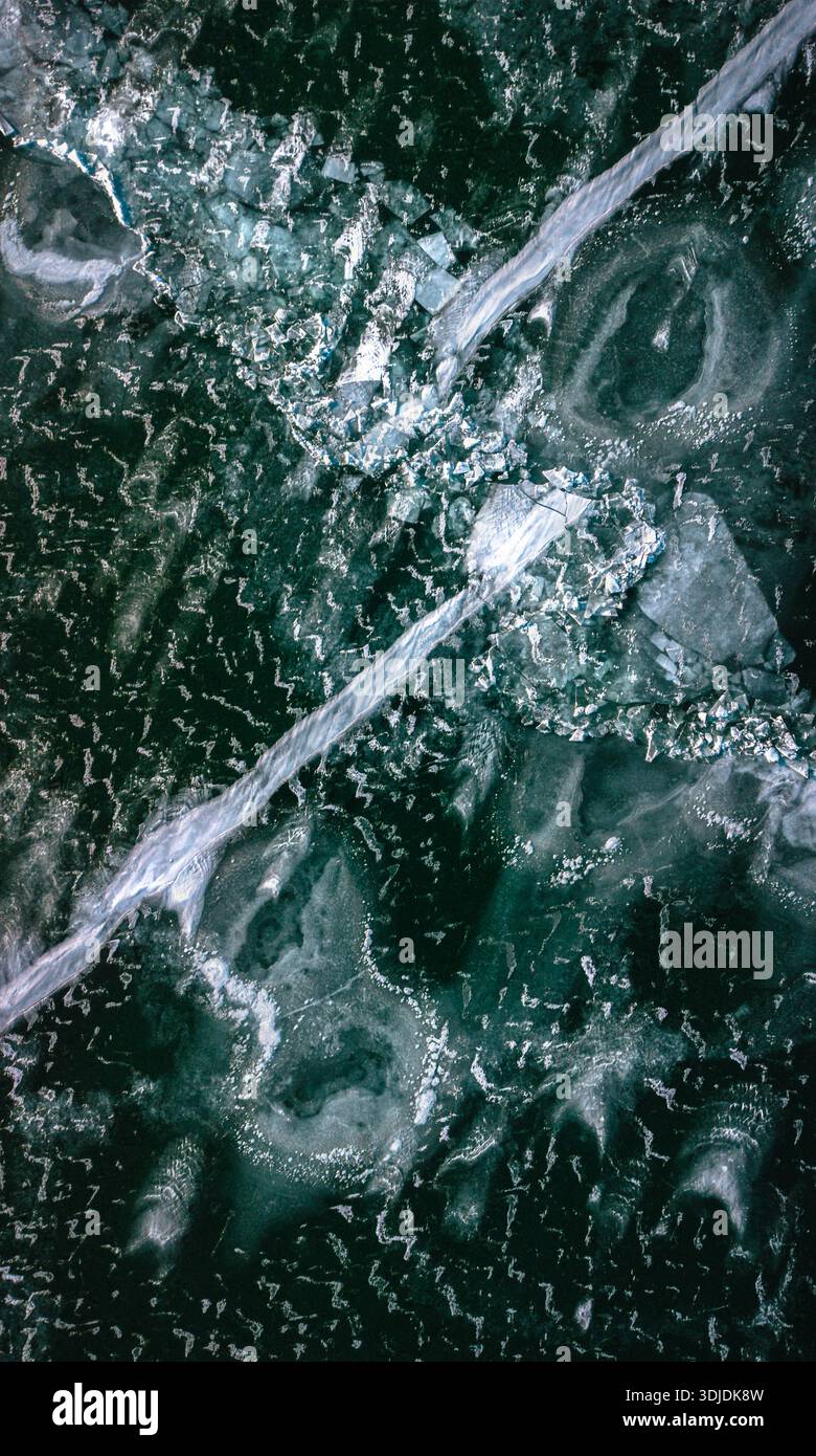 Vista aerea di un vasto lago ghiacciato, la sua superficie un arazzo di smeraldo e bianco smerigliato, inciso con crepe frastagliate e motivi vorticosi, Siófok, Somo Foto Stock