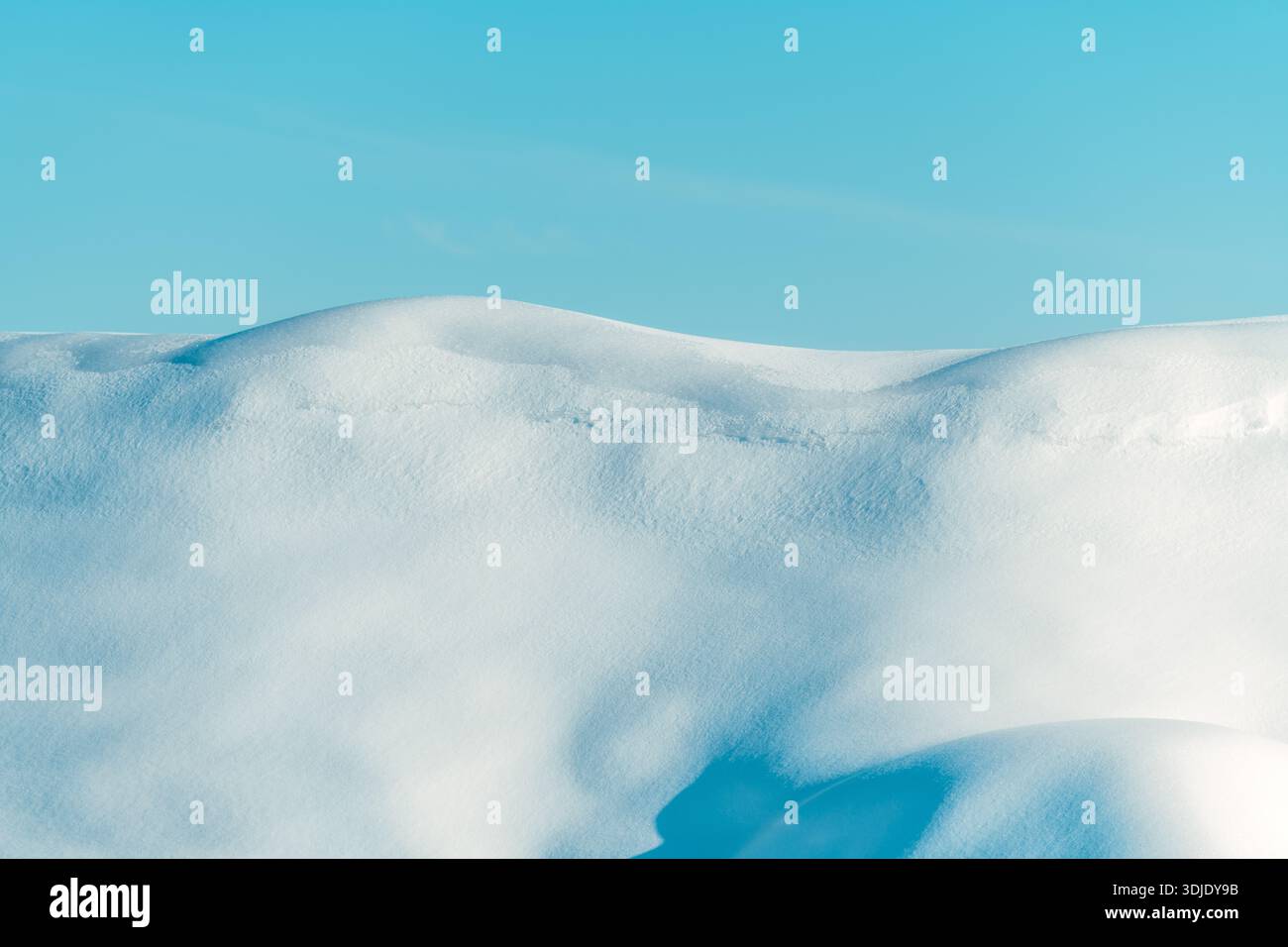 Dolci colline innevate contro il cielo invernale azzurro, paesaggio minimale Foto Stock