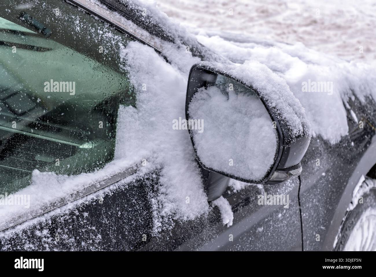 Specchietto laterale e finestrino laterale dell'auto ghiacciati con goccioline di ghiaccio durante l'inverno estremo. Rappresentazione visiva di forti nevicate, basse temperature, e. Foto Stock