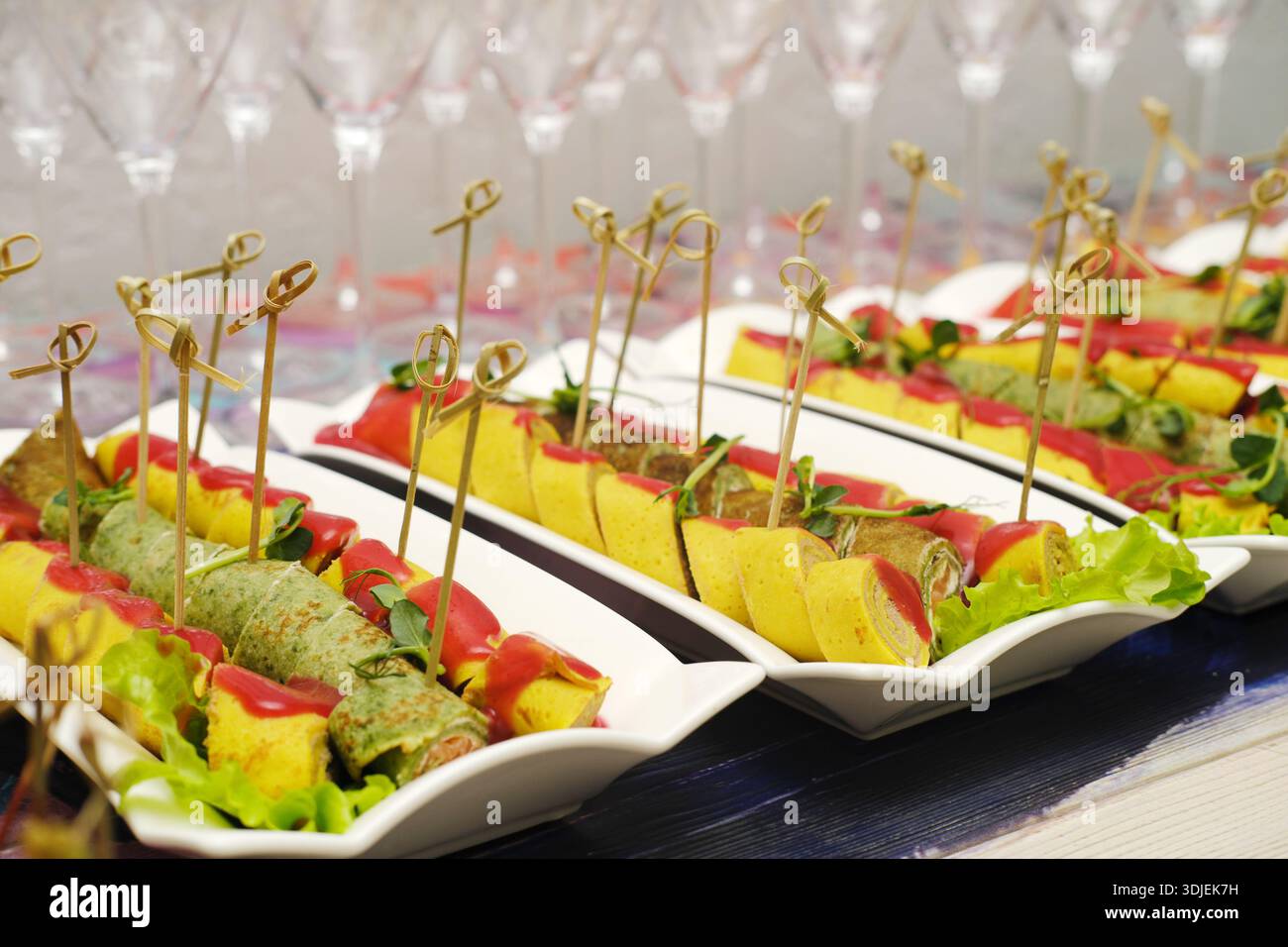 Stuzzichini gourmet disposti su piatti bianchi, decorati con erbe aromatiche, creano un'atmosfera invitante per eventi, mettendo in risalto la creatività culinaria e. Foto Stock