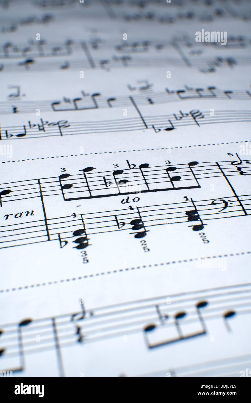 Una vista ravvicinata degli spartiti si estende su una superficie piana. Le note e i simboli forniscono istruzioni per la pratica del pianoforte. Questa scena sembra provenire da un musi Foto Stock