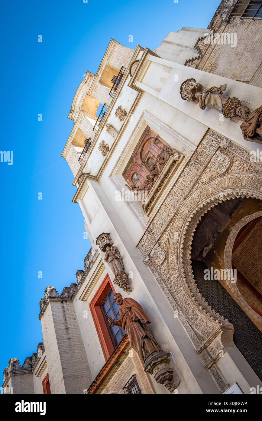 Un edificio storico ornato catturato da una prospettiva bassa, che mette in risalto un arco decorato con cura e figure in pietra scolpite. Foto Stock