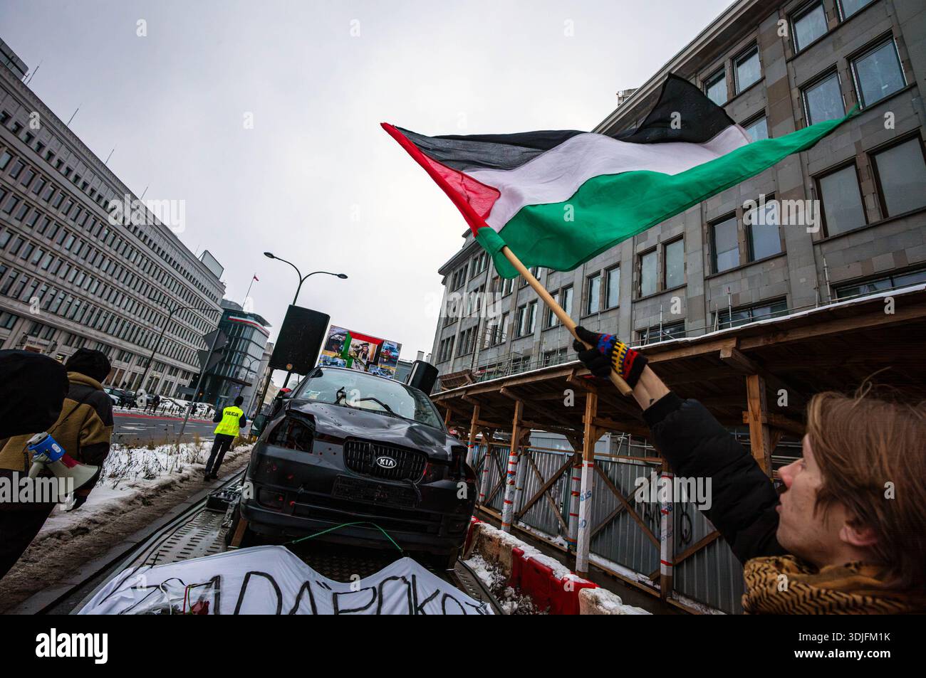 Un manifestante inonda una bandiera palestinese sopra il proiettile Kia Picanto. Nel pomeriggio di domenica 25 gennaio, i manifestanti pro-palestinesi e anti-genocidio si sono riuniti al Palazzo Presidenziale di Varsavia per celebrare il secondo anniversario dell'assassinio israeliano di Hind Rajab, di cinque anni. Dopo i discorsi, i manifestanti marciarono dietro un proiettile Kia Picanto verso l'ambasciata americana, poi verso il Parlamento della Repubblica di Polonia. Il 29 gennaio 2024, dopo che l'auto della sua famiglia è stata colpita dalle forze israeliane durante la fuga, Hind Rajab è sopravvissuta per ore nella Kia Picanto di suo padre, California Foto Stock