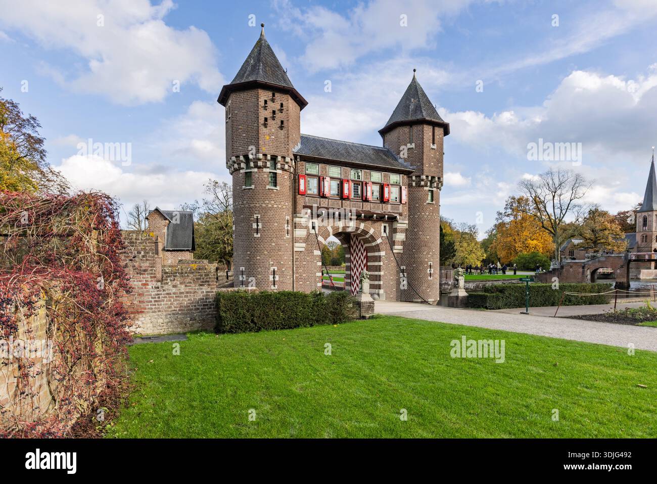 Una monumentale porta di ingresso in mattoni con torri gemelle e un ponte levatoio all'ingresso del parco del castello De Haar nei Paesi Bassi sotto un cielo blu. Foto Stock