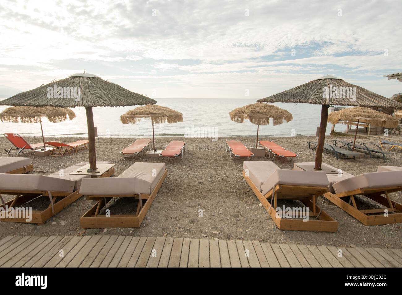 Spiaggia vuota con lettini e ombrelloni di paglia all'alba Foto Stock
