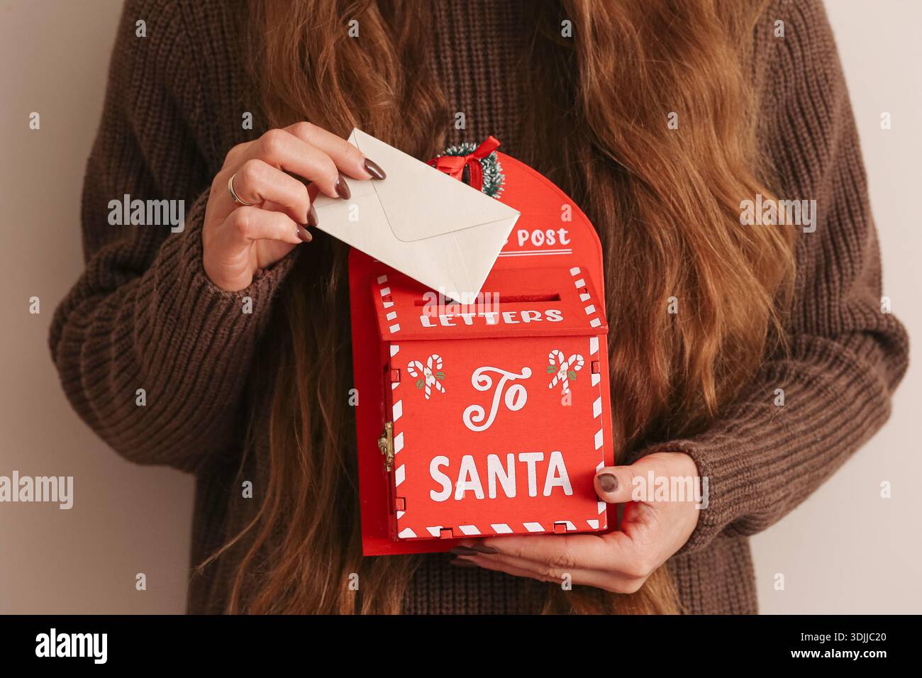 Donna che tiene la cassetta delle lettere di Babbo Natale. Concetto di tradizione natalizia. Scatola per posta rossa per le feste con busta. Festa della stagione invernale. Foto Stock