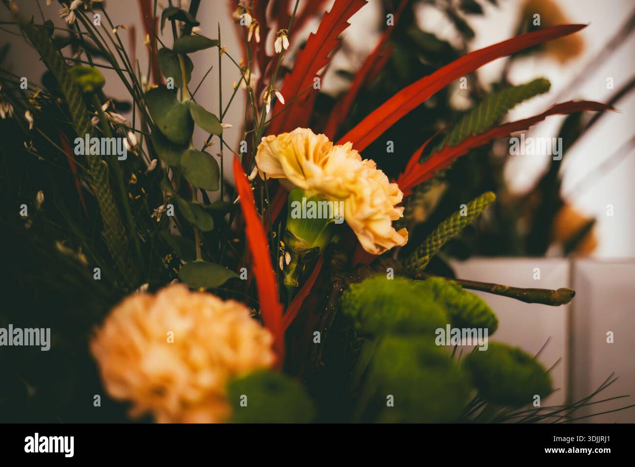 Composizione floreale Moody con garofani arancioni e crisantemi verdi. Foto Stock