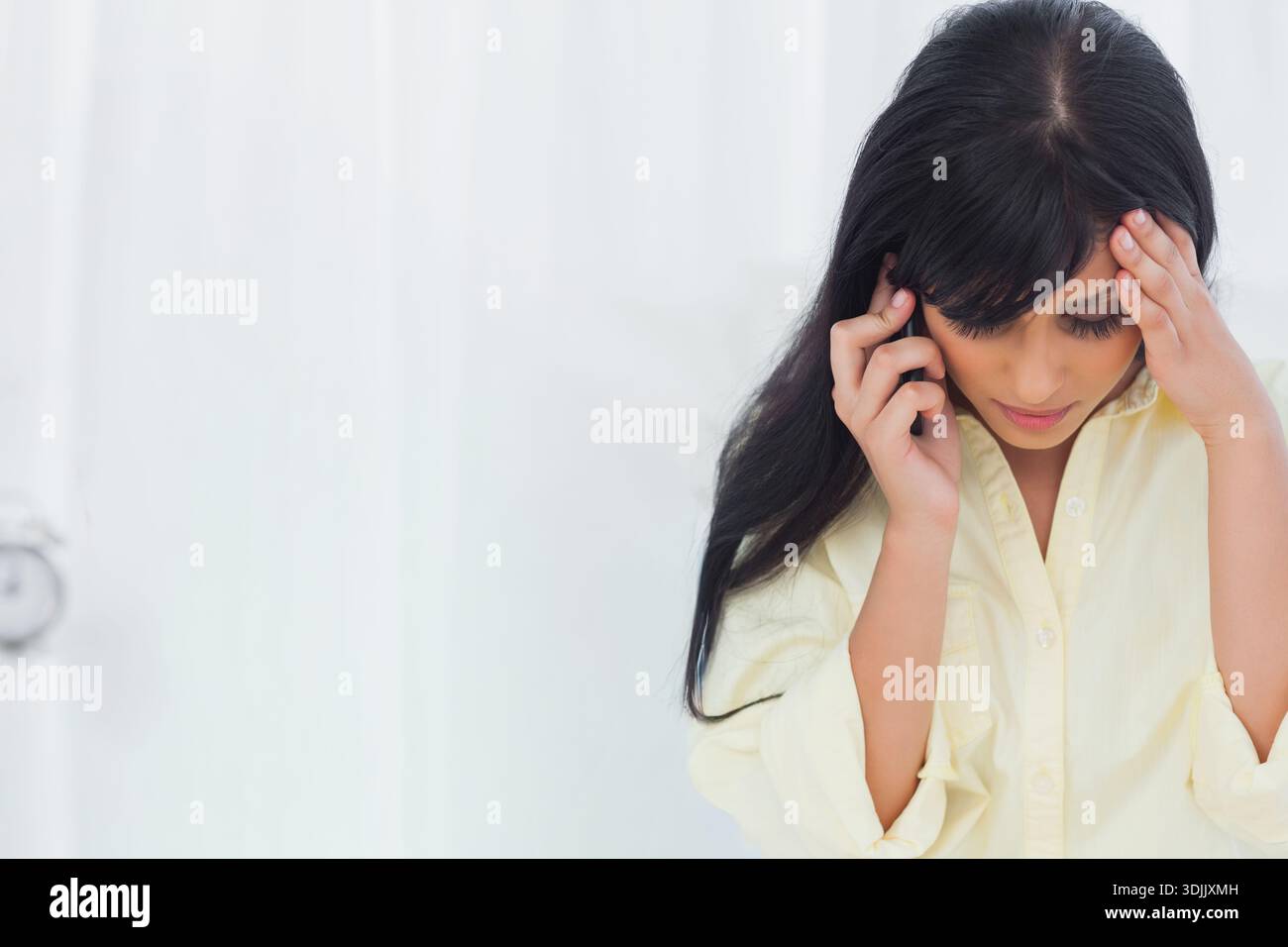 Telefono appoggiato sul comodino mentre la sveglia analogica ticchetta da tende e spazio per le copie. Donna, ansia, stile di vita, minimalista, alto, letto Foto Stock