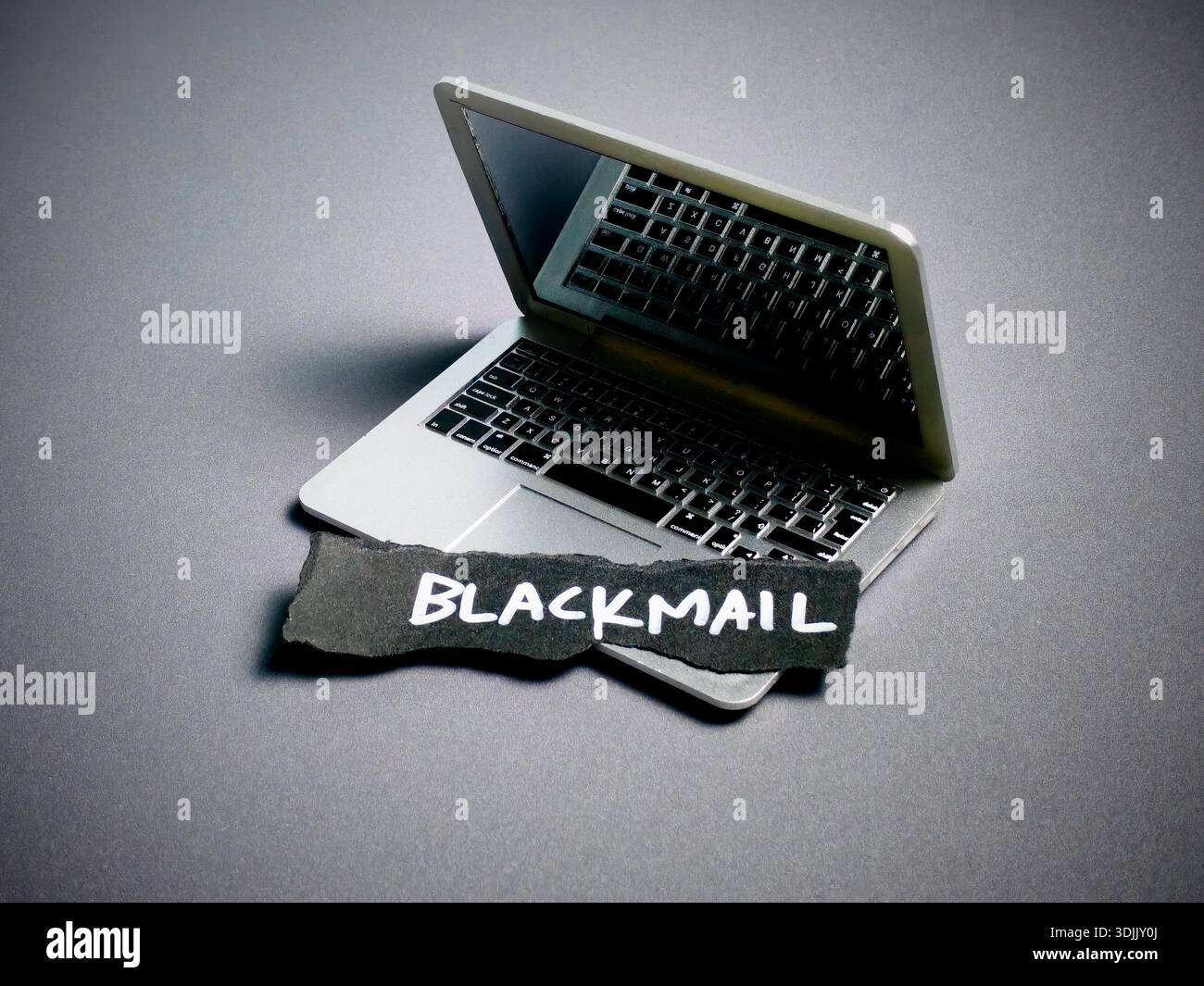 Carta strappata con testo ricatto sulla tastiera del notebook che rappresenta le minacce digitali Foto Stock