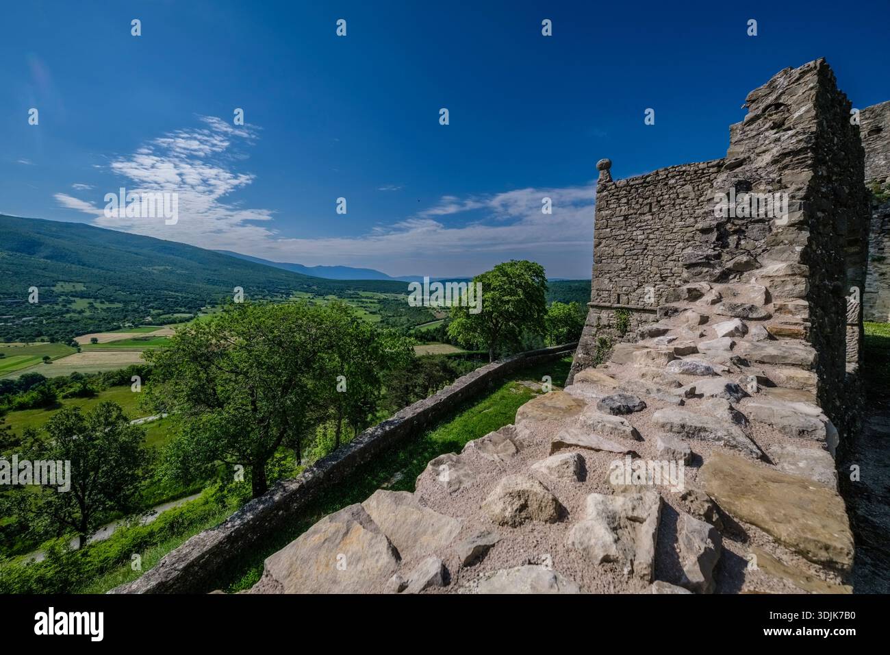 Mura di pietra del castello di Boljun. Valle verde e le pendici della catena montuosa Učka sotto un cielo blu in lontananza. Foto Stock