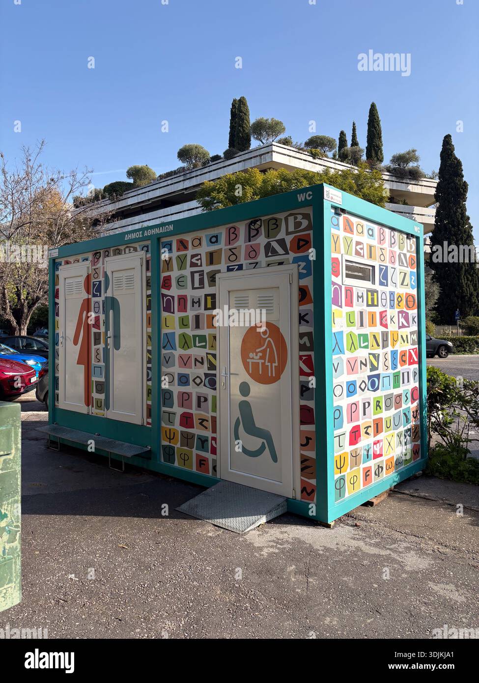Public WC, Dimos Athinion, Atene, Grecia. Moderno bagno accessibile con sedia a rotelle, decorato con lettere greche colorate e simboli alfabetici. Foto Stock