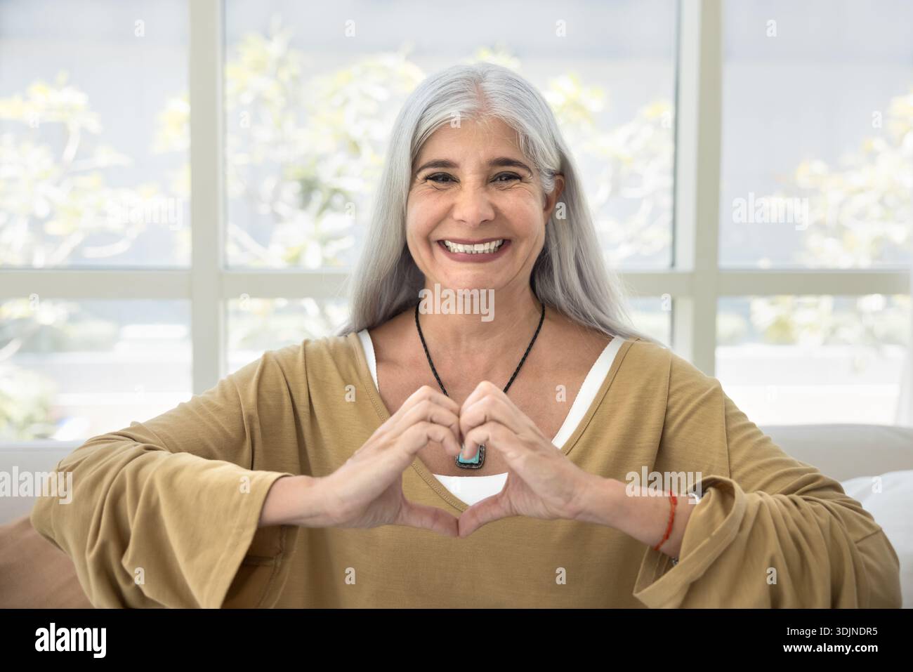 Gioiosa donna di mezza età che fa gesti cardiaci con le mani Foto Stock