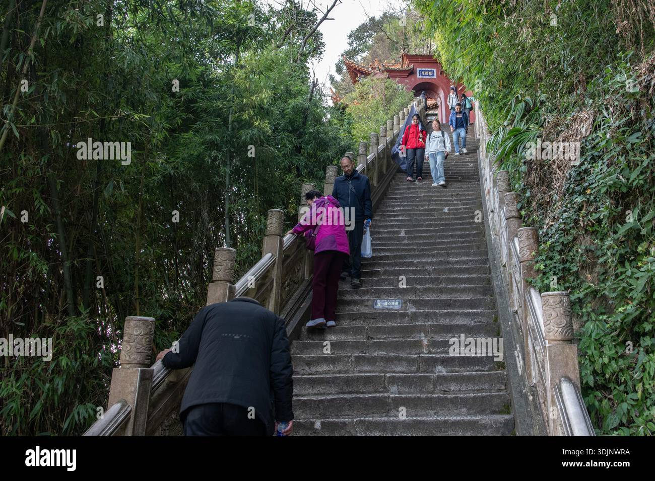 I visitatori anziani del monte Xishan scendono da una ripida scalinata in pietra. Kunming, Yunnan, Cina. Foto Stock
