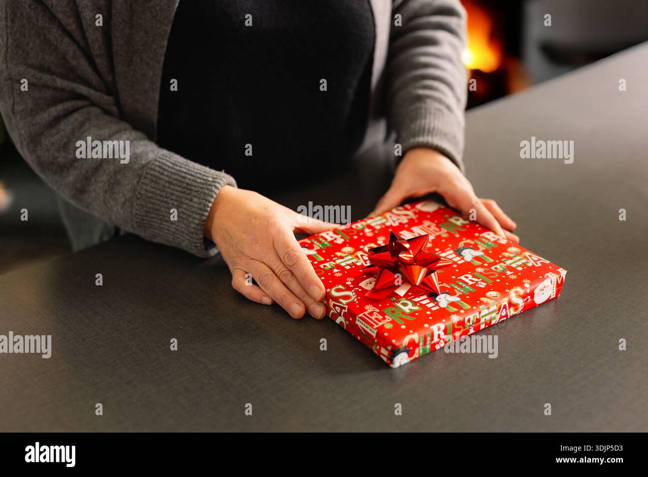 Dettaglio di una donna che prepara con cura una confezione regalo di Natale con nastro e carta da imballaggio. Foto Stock