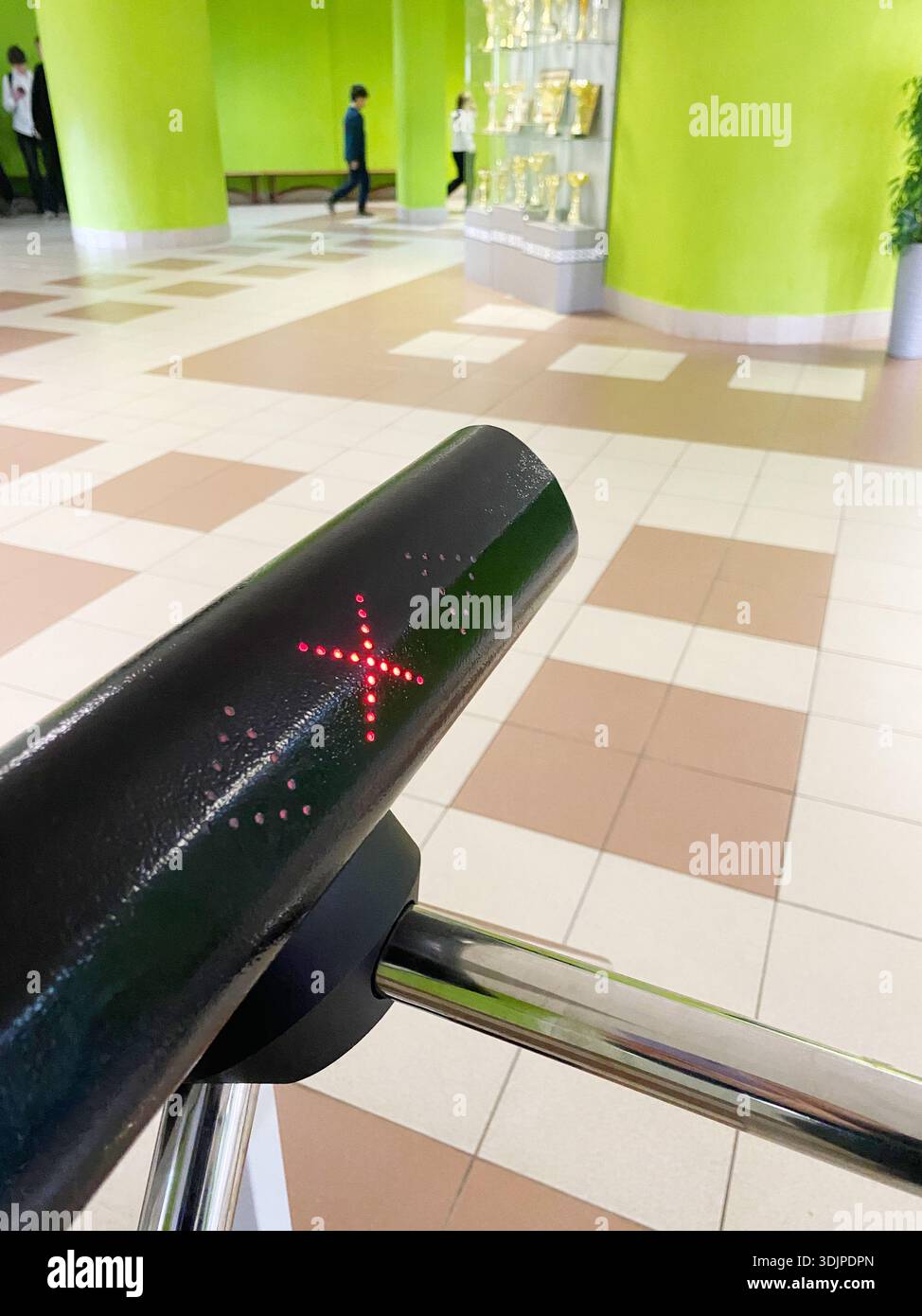 Sistema di controllo degli accessi con indicatore luminoso rosso, posizionato in un ambiente scolastico colorato, che mette in evidenza le misure di sicurezza e gli studenti moni Foto Stock