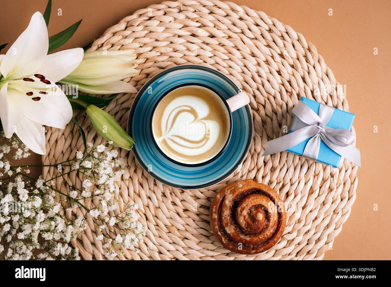 Tazza di caffè con pasta alla cannella, fiori e piccola scatola regalo disposta su un tovagliolo intrecciato. Happy Valentines Day. Vista dall'alto, disposizione piatta. Foto Stock
