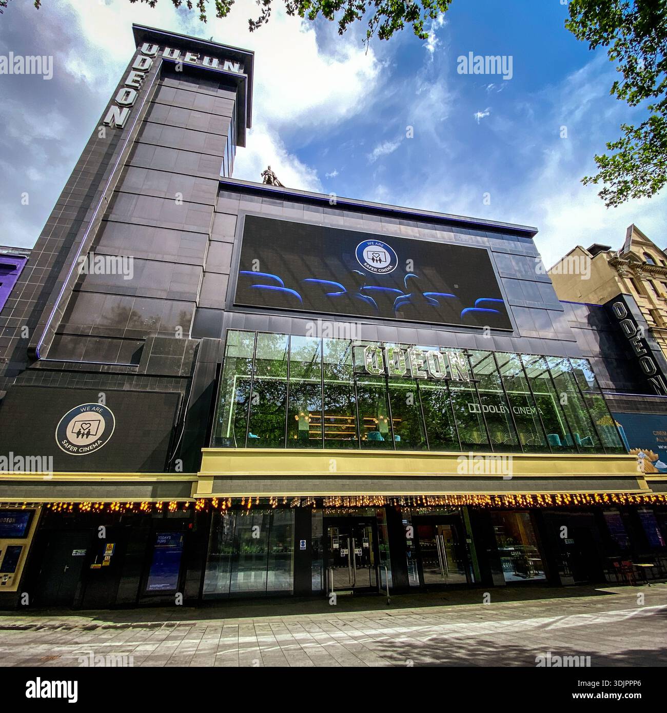Vista esterna del cinema Odeon in Leicester Square a Londra, che mostra la moderna facciata in vetro, la torre e lo schermo digitale che promuovono film sotto un bri - Immagine stock catturata con smartphone