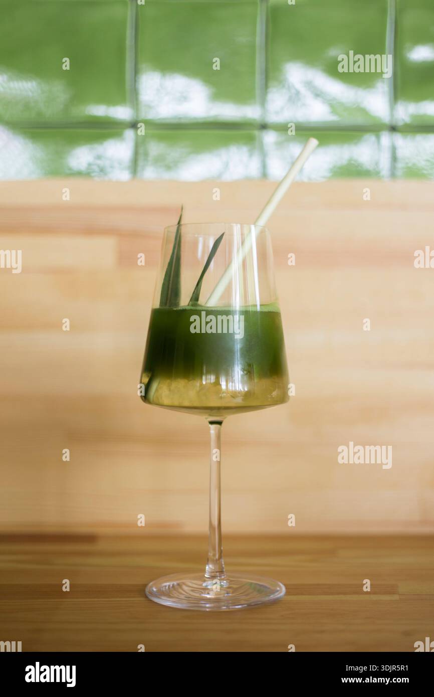 Preparazione di latte giapponese matcha freddo, tè verde con latte, latte di soia, strumenti tradizionali matcha, con paglia di bambù in vetro su sfondo in legno. Foto Stock