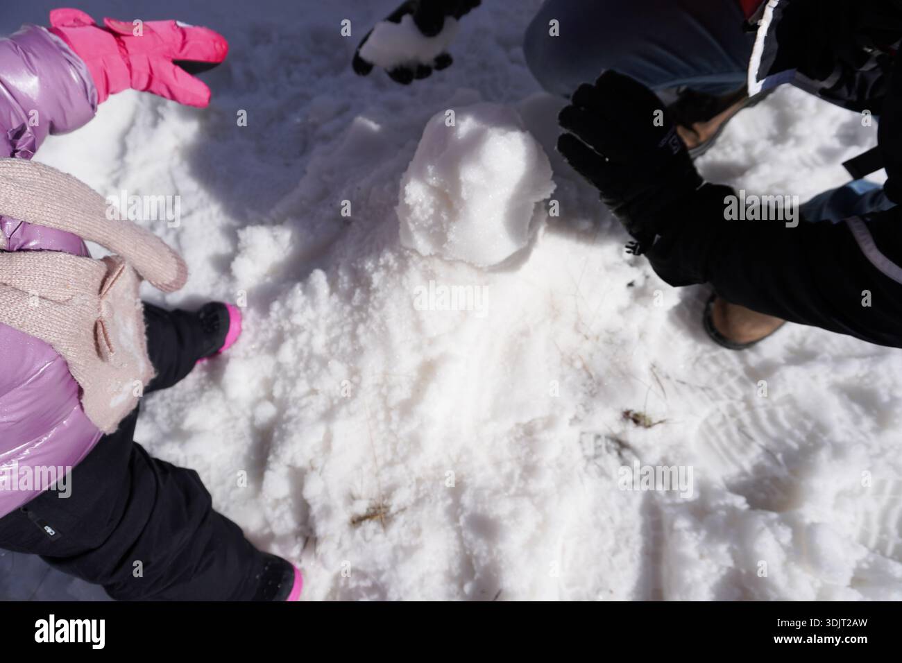 Padre e figlia fanno un pupazzo di neve. Bambino e suo padre che paiano con la neve. Vista ravvicinata dell'uomo che raccoglie neve bianca fresca da terra. Foto Stock