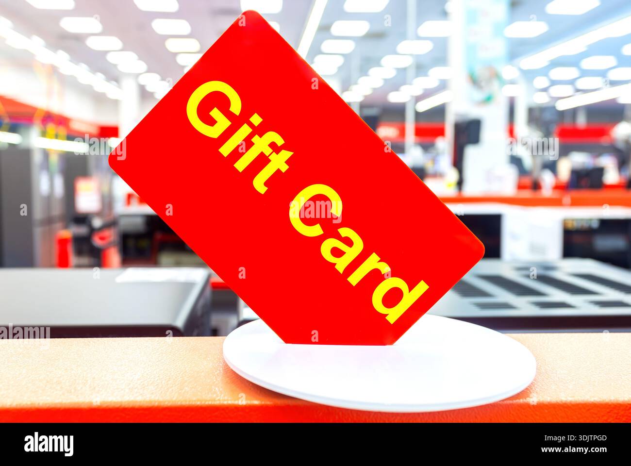 Buono regalo rosso su sfondo sfocato nel negozio di elettronica, primo piano Foto Stock