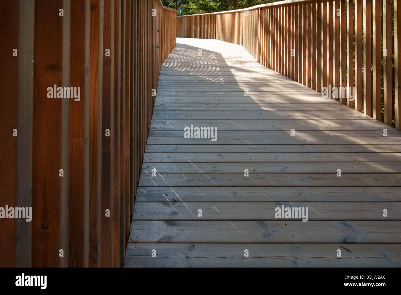Architettura silenziosa ritmica mostrata in passerella vuota in legno con ringhiere ripetute e motivi ombrosi morbidi, struttura minimale nordica che enfatizza i materi Foto Stock