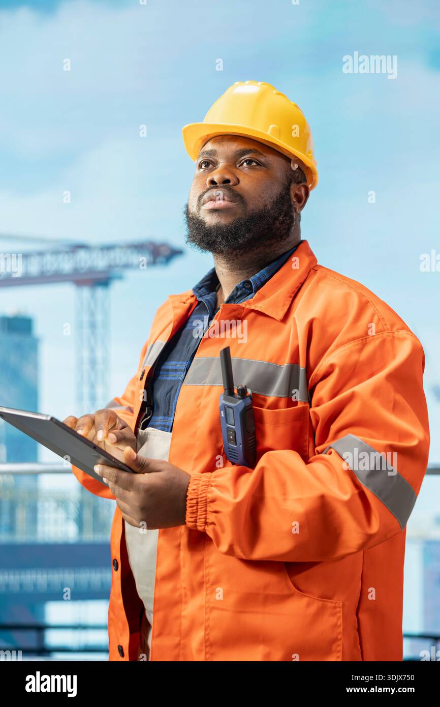 Il dipendente della piattaforma offshore supervisiona le operazioni del deck con il dispositivo, garantendo la conformità ai protocolli di sicurezza. Ingegnere afroamericano che esegue la manutenzione preventiva degli attrezzi per trivellazioni Foto Stock