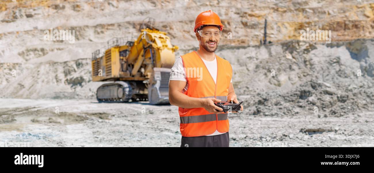 Operatore di droni con giubbotto riflettente e casco su una fossa mineraria Foto Stock