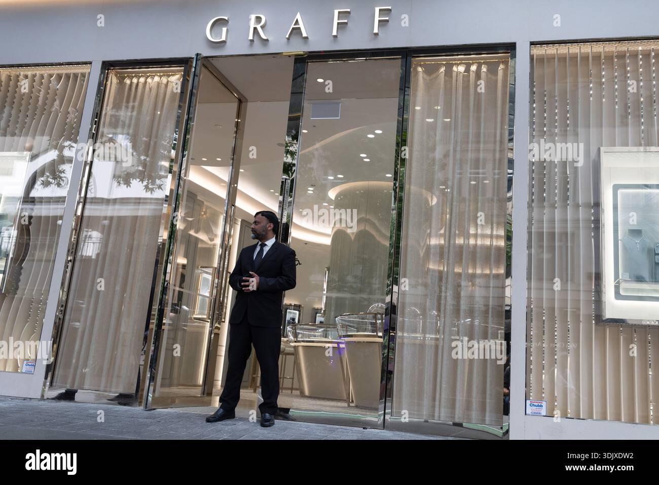 Una guardia di sicurezza si trova fuori da una boutique di gioielli di lusso Graff in Queen Street nel centro di Auckland, nuova Zelanda. Foto Stock