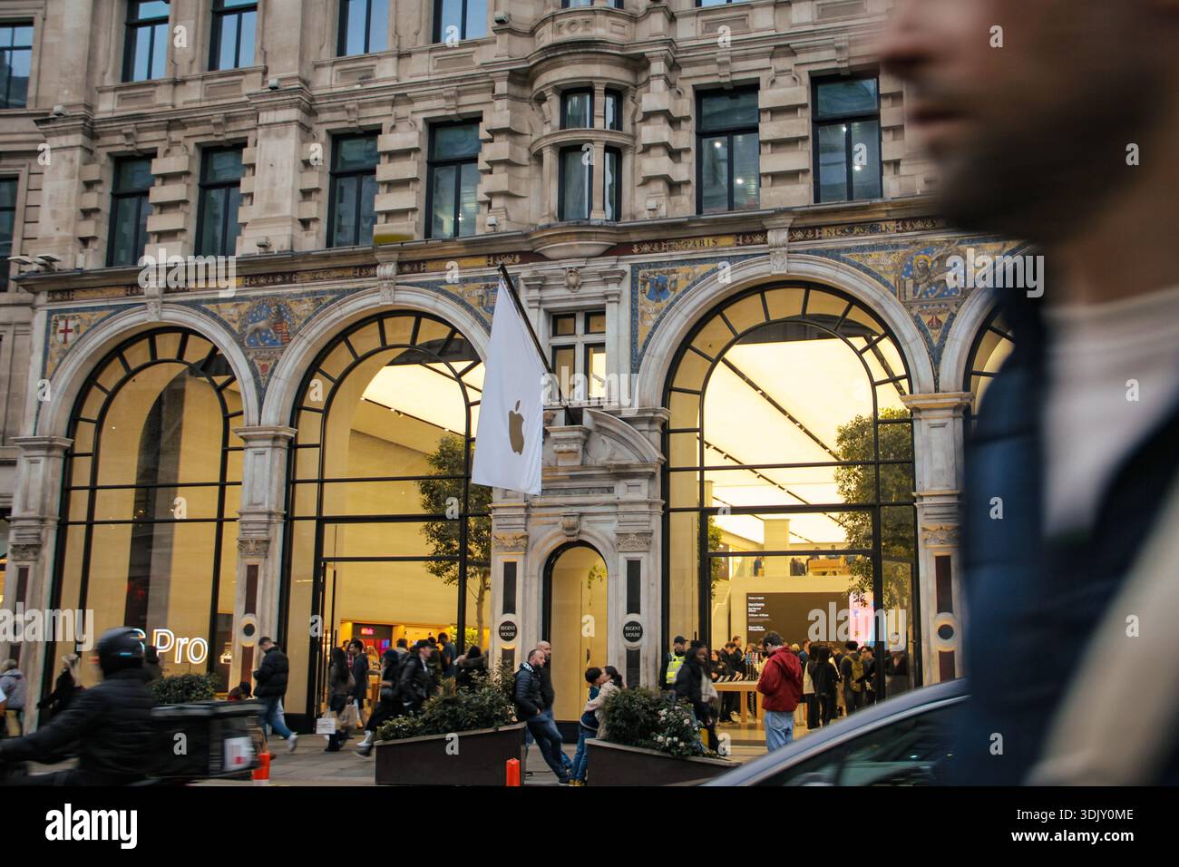 Ingresso all'Apple Store in uno storico edificio neoclassico con archi ornati, bandiera bianca con logo e pedoni in un ambiente vivace del centro città. Foto Stock