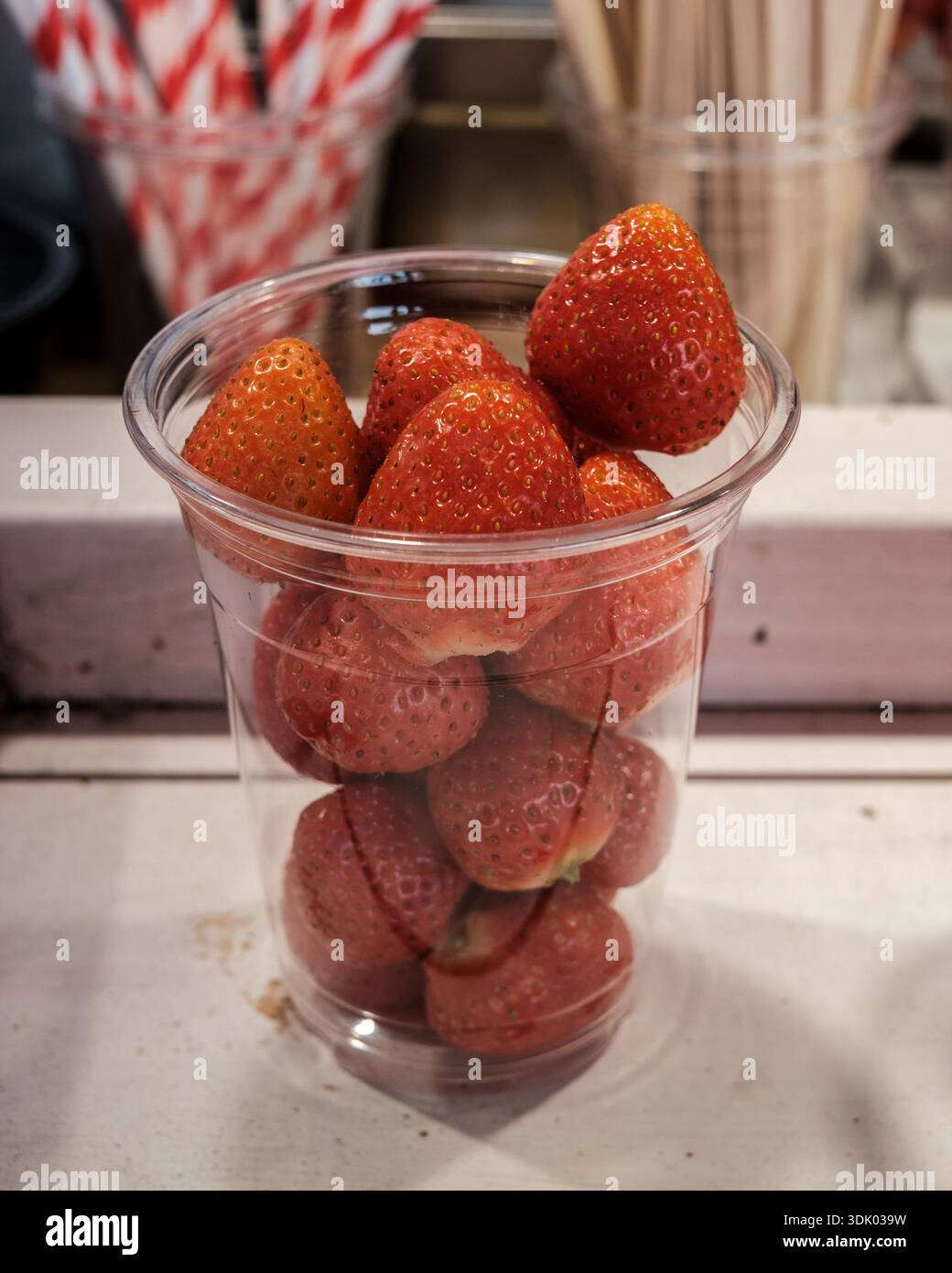Fragole fresche servite in una tazza di plastica trasparente presso uno stand di Street food, pronte da mangiare come semplice spuntino di stagione. Foto Stock