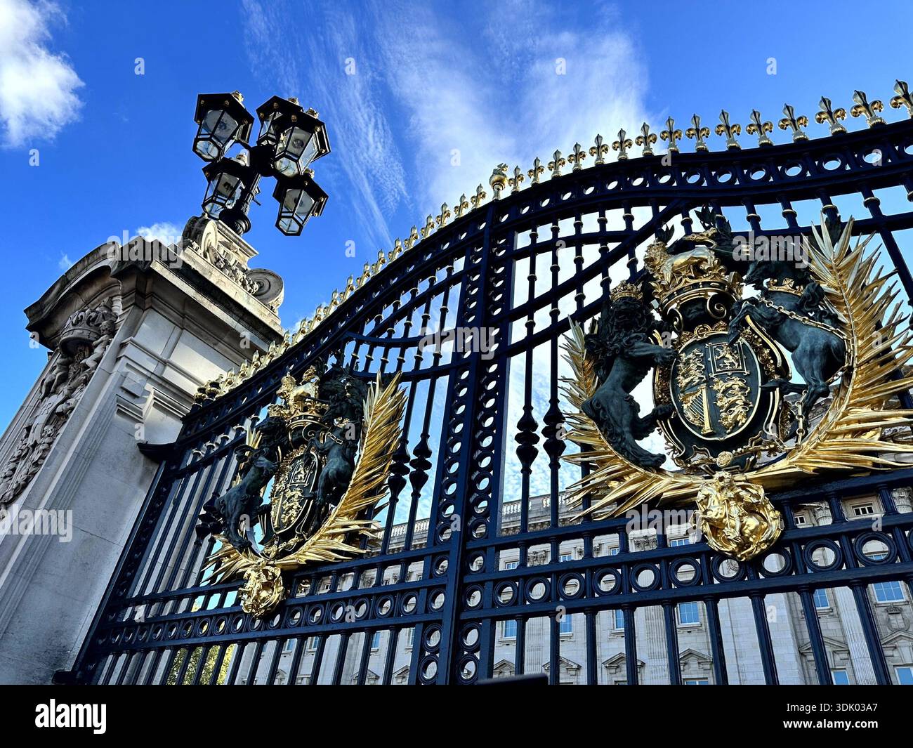 Porte ornate di Buckingham Palace a Londra, con stemmi reali dorati e storiche ferriere sotto un cielo blu. - Immagine stock catturata con smartphone