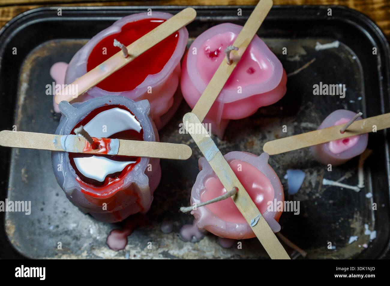 Una prospettiva dall'alto verso il basso di cera rossa e rosa versata negli stampi in silicone. Foto Stock