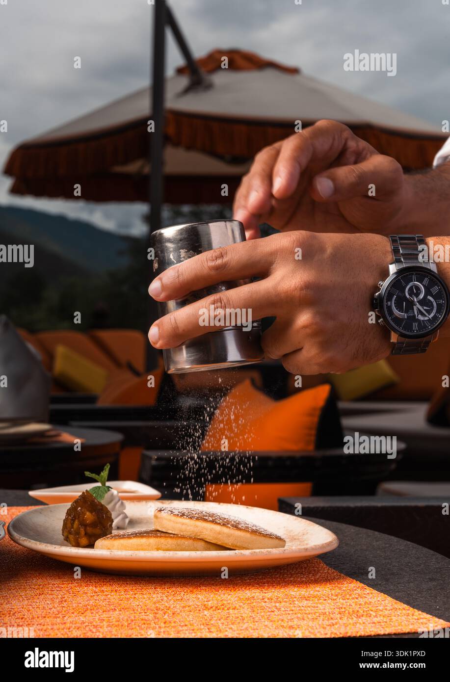 Spolverare zucchero a velo su un dessert rivestito all'aperto Foto Stock