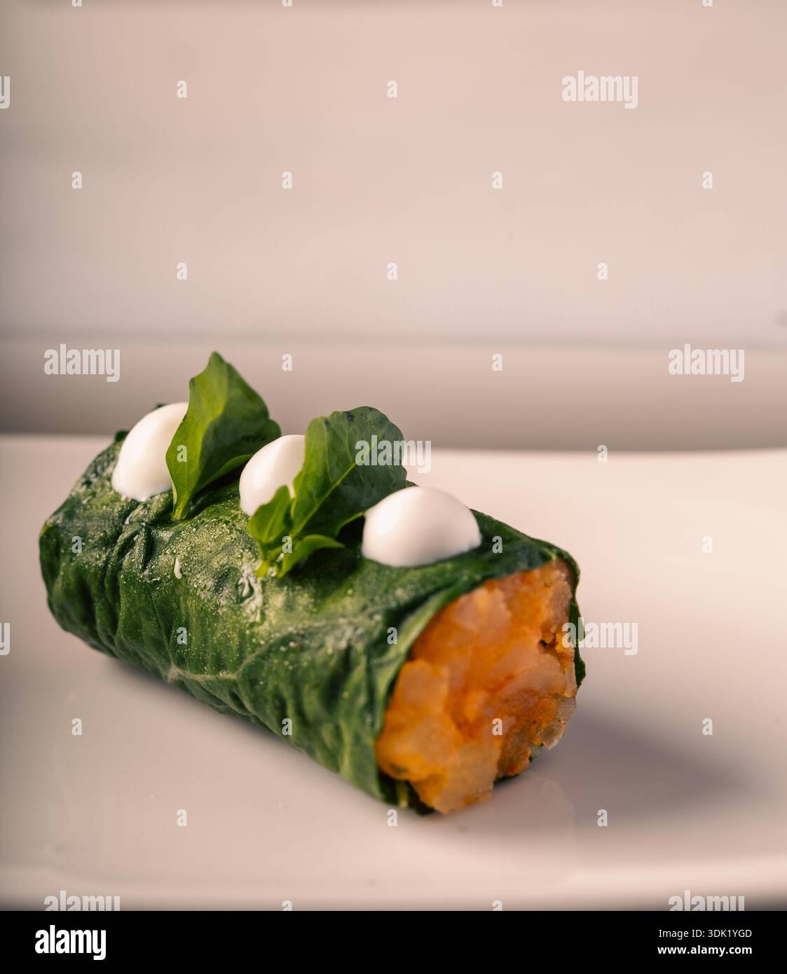 Elegante rotolo avvolto in foglia verde con gocce di crema Foto Stock