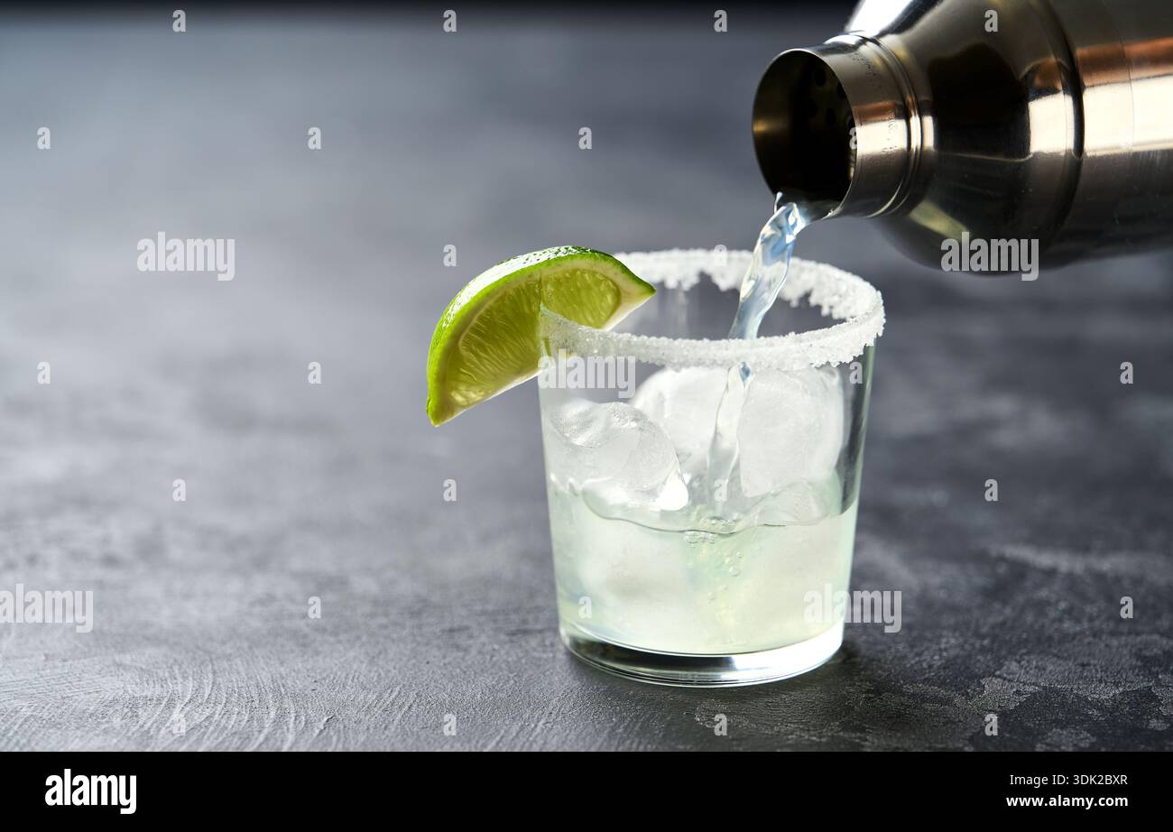 Il barista versa un cocktail di margarita al lime in un primo piano di bicchieri. Foto Stock