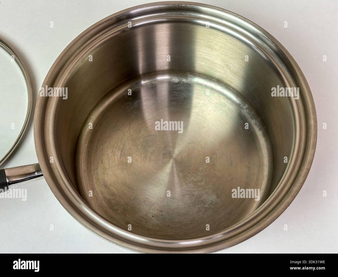 Primo piano di una padella vuota in acciaio inox con coperchio parziale a lato su sfondo chiaro neutro - Immagine stock catturata con smartphone