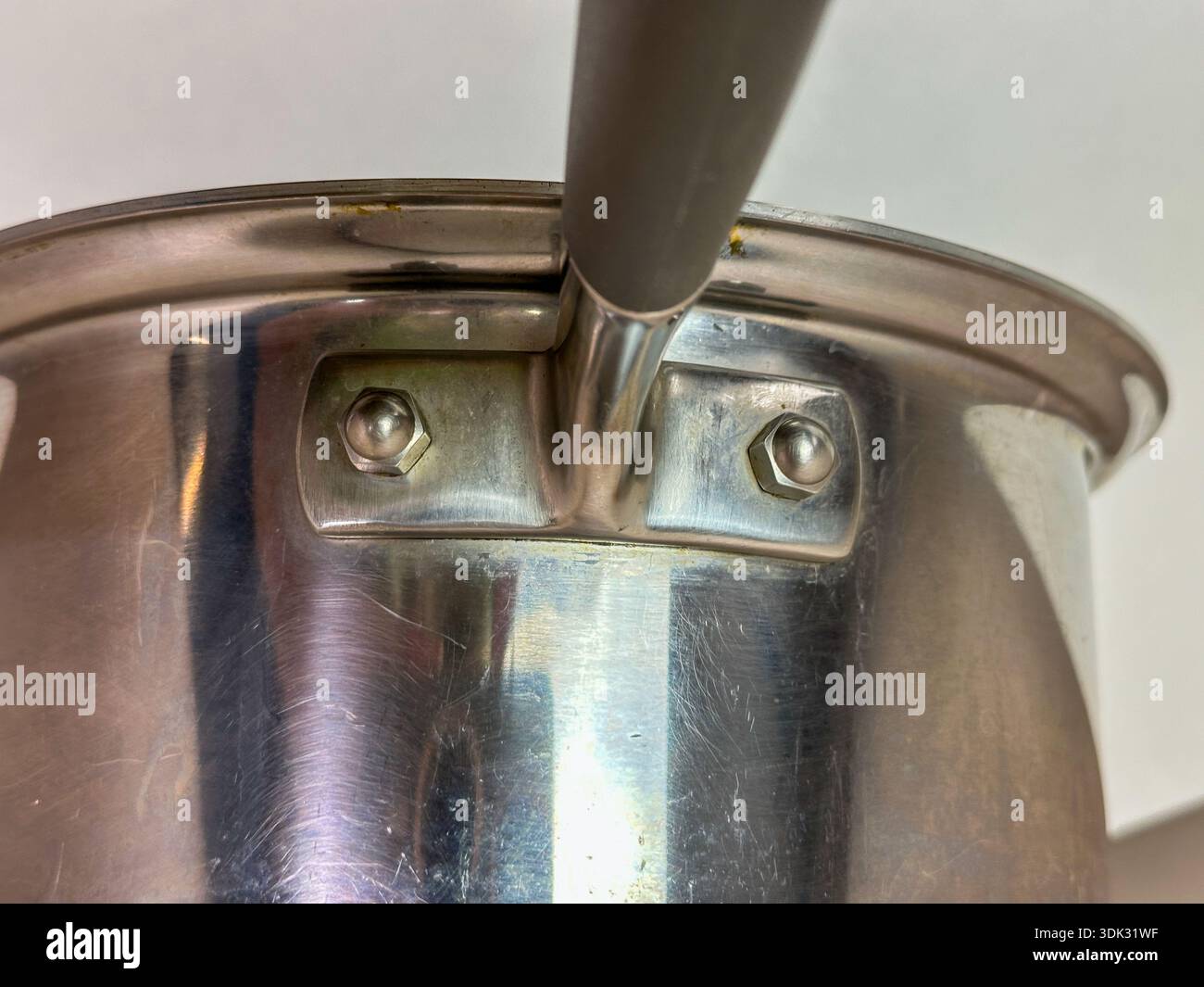 Primo piano da sotto di una padella per salsa in acciaio inossidabile su sfondo bianco - Immagine stock catturata con smartphone
