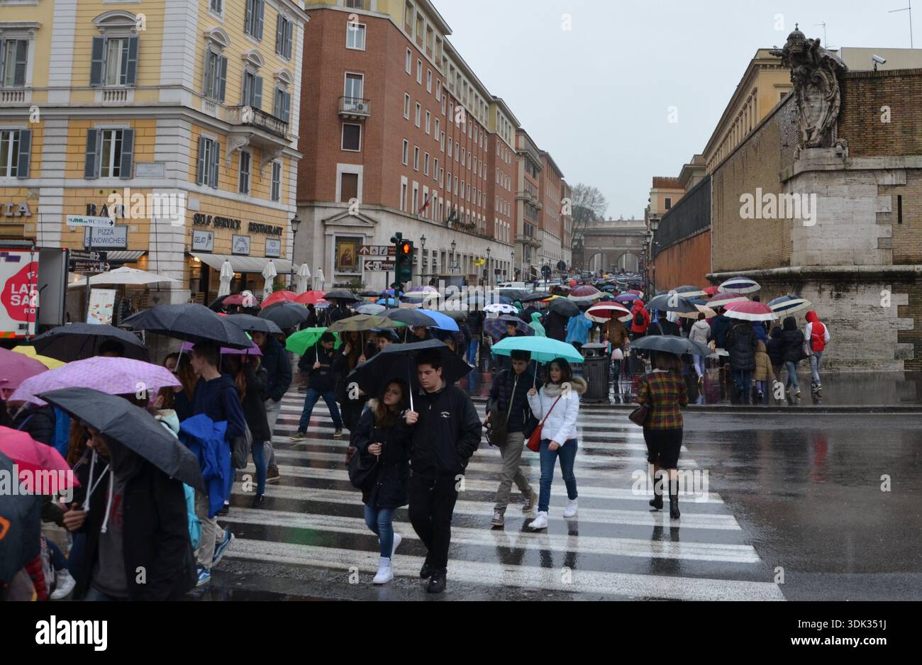 I pedoni attraversano la strada sotto la pioggia battente nel centro di Roma, Italia Foto Stock
