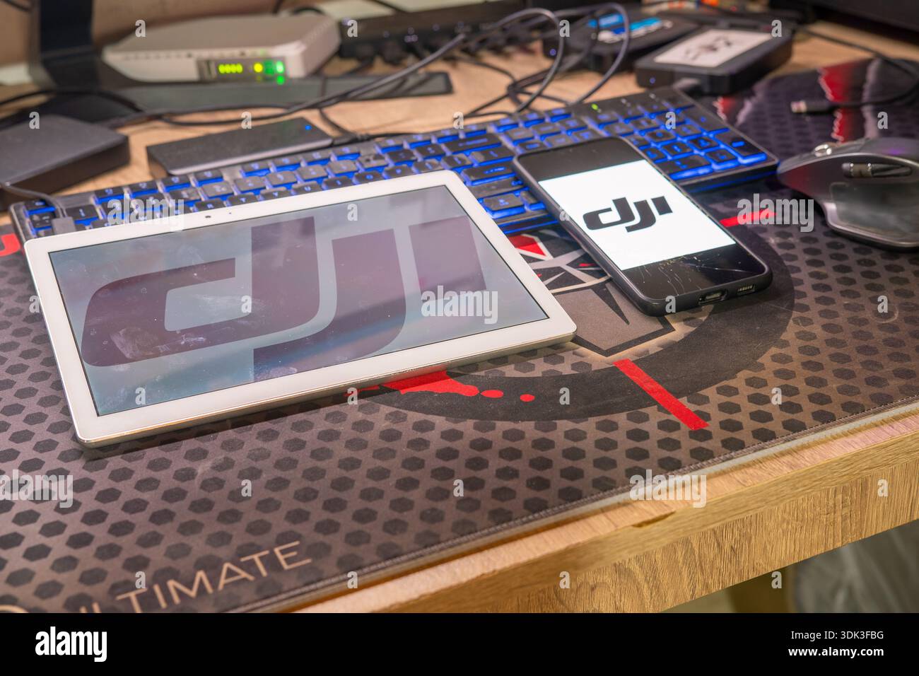 Tablet bianco e smartphone nero con logo DJI per l'applicazione Drone Flight Control appoggiata sulla superficie della scrivania del computer Foto Stock