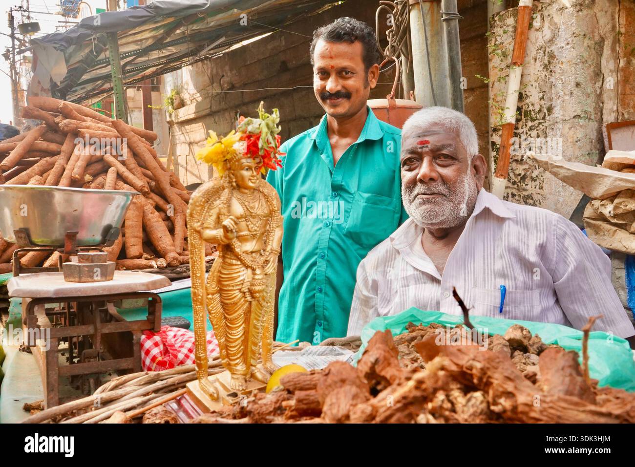 Venditore ambulante che vende verdure a radice e statua della dea indù al mercato di Trichy, Tamil Nadu, India Foto Stock