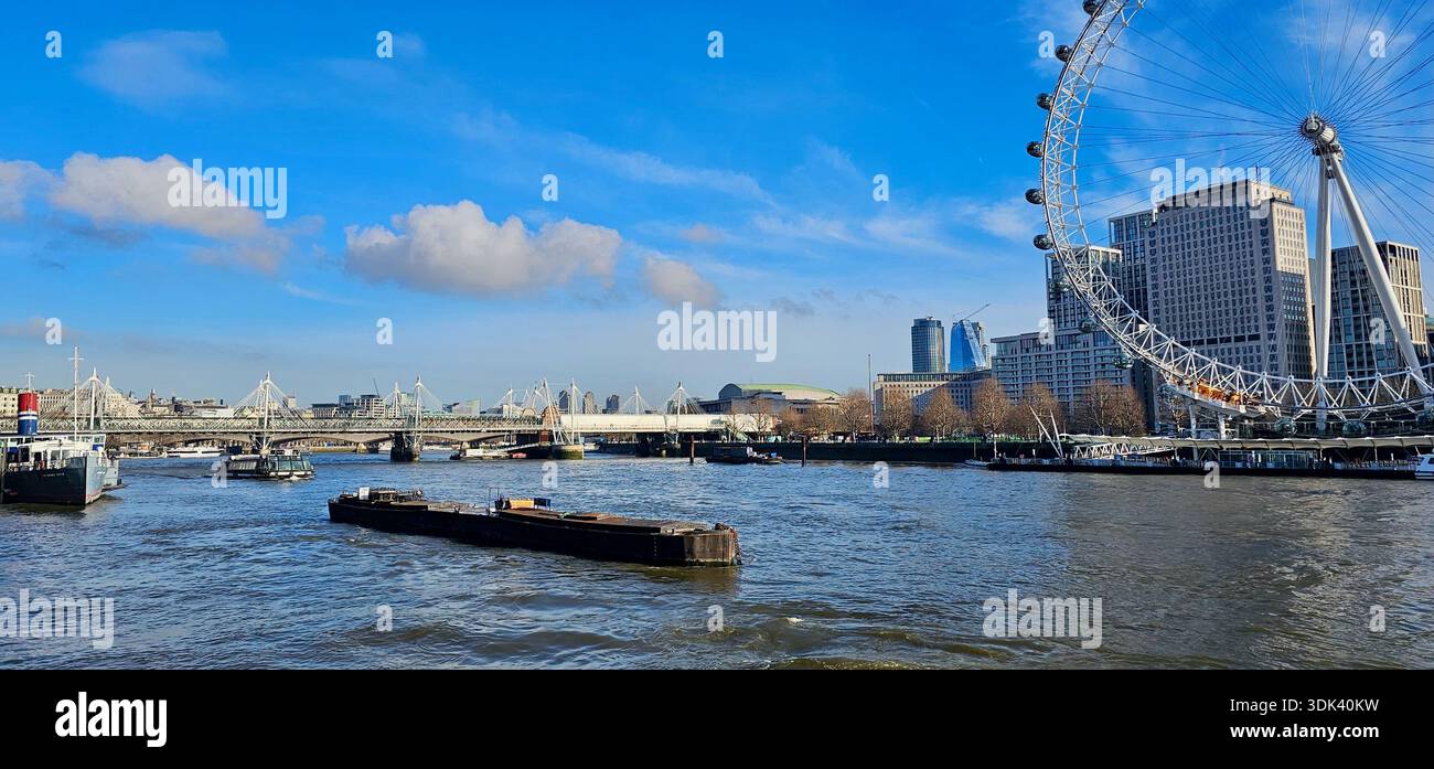 Una vivace scena sul lungofiume con il London Eye, il Tamigi e una barca passeggeri, che cattura il turismo urbano e l'architettura iconica lungo il Foto Stock